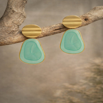 Gold and turquoise earrings on a branch with a natural background