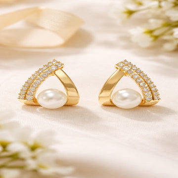 Gold earrings with pearls and gemstones on a soft background