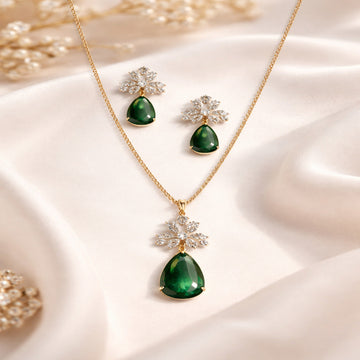 Green teardrop necklace with matching earrings on a soft fabric background