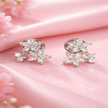 Pair of silver floral earrings on a pink fabric background