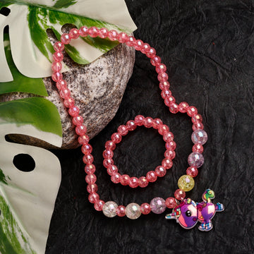 Pink beaded bracelet with a colorful charm on a dark textured surface with leaves.