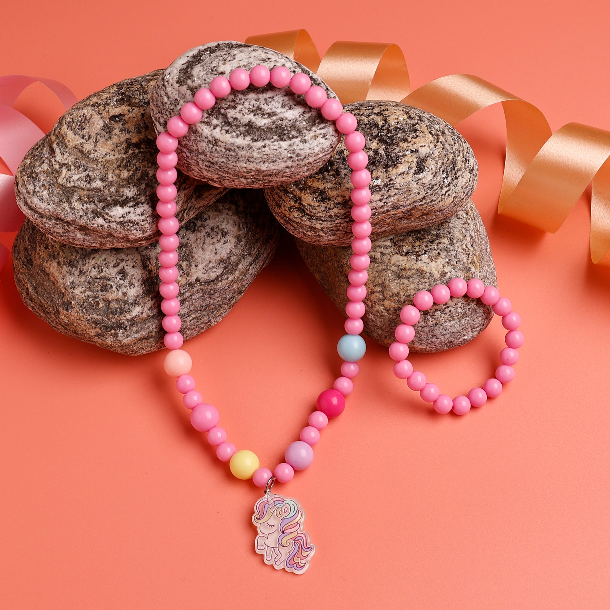 Pink beaded necklace with a pendant on a peach background