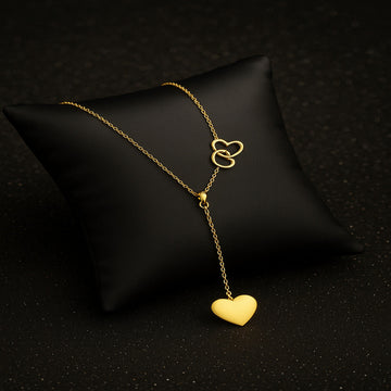 Gold necklace with heart pendant on a black pillow