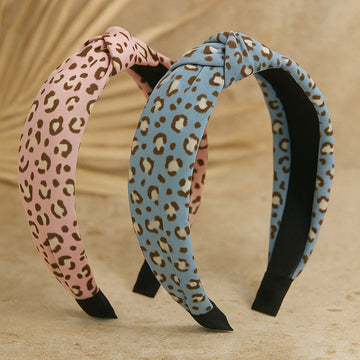 Two leopard print headbands, one pink and one blue, on a beige background.