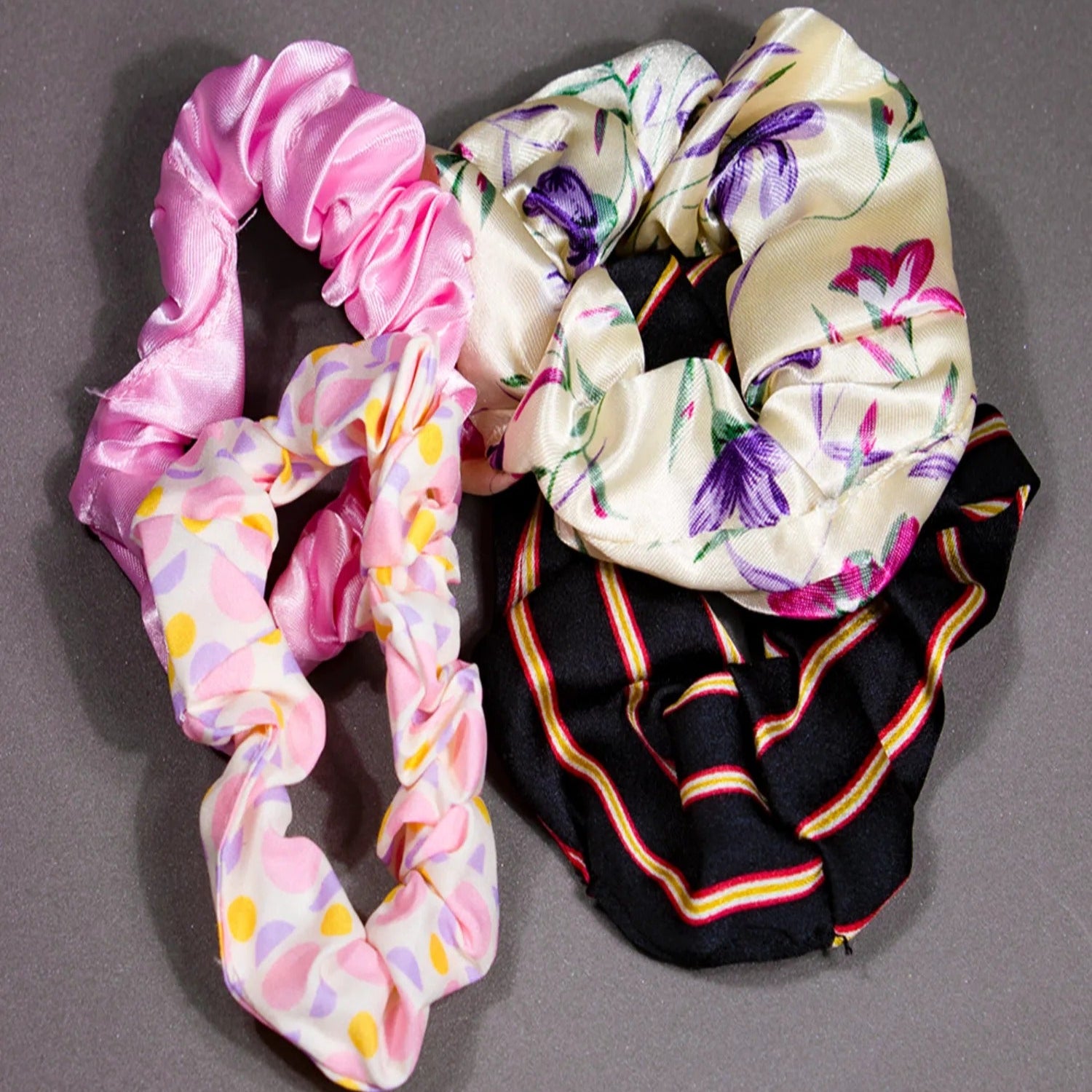 Three colorful scrunchies on a gray background