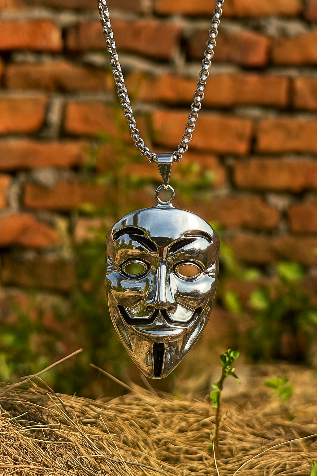 Silver mask pendant necklace against a brick wall background