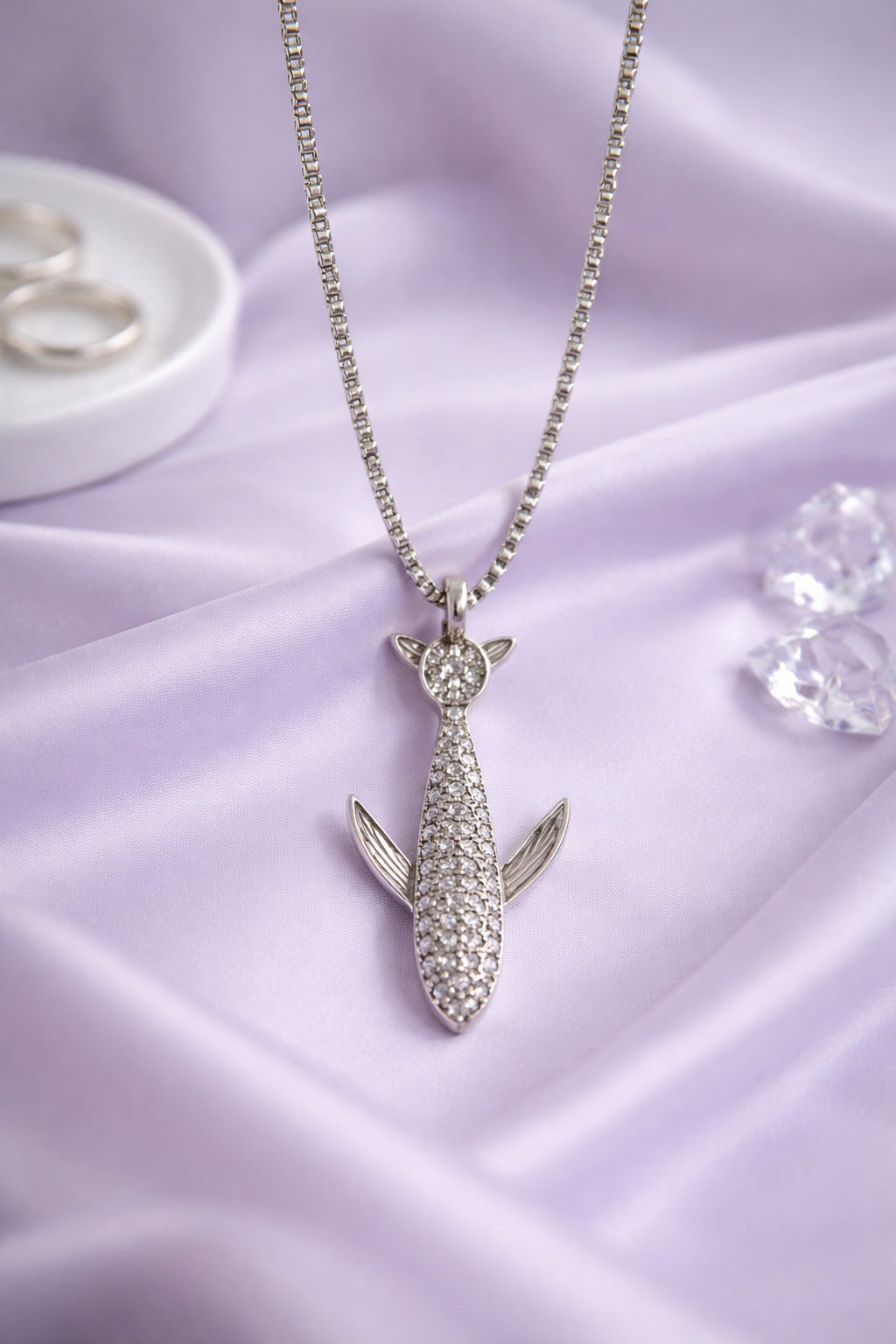 Silver cat-shaped pendant necklace on a purple fabric background