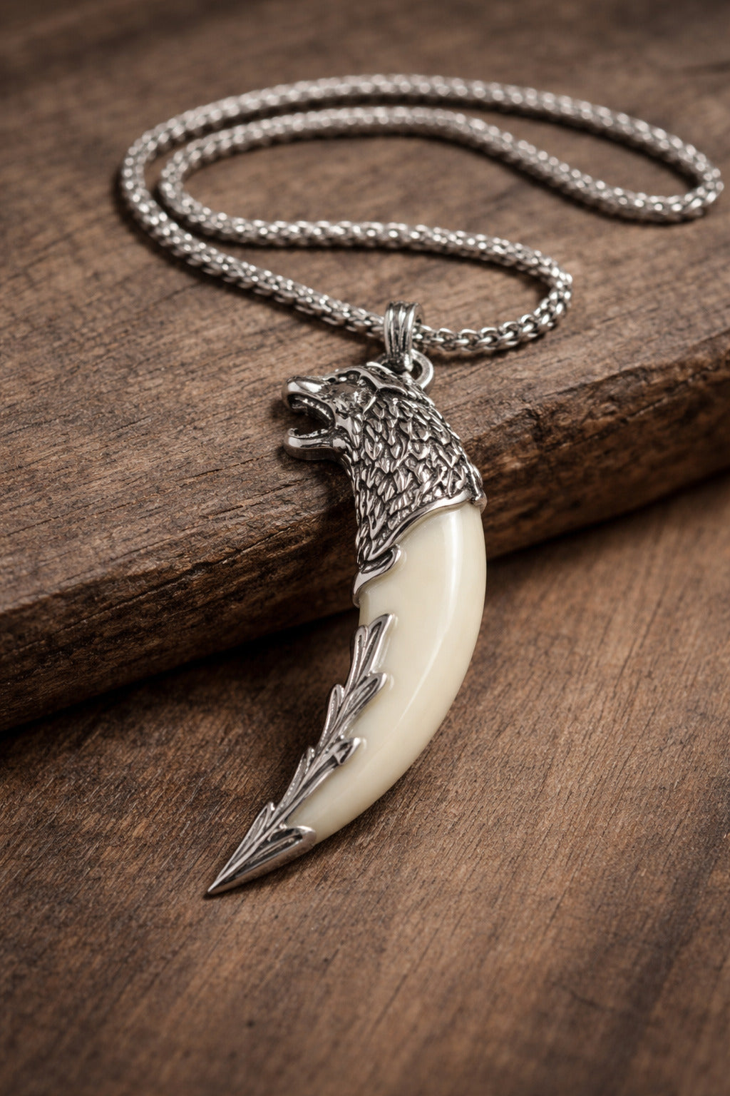 Silver necklace with a wolf head and bone claw pendant on a wooden surface