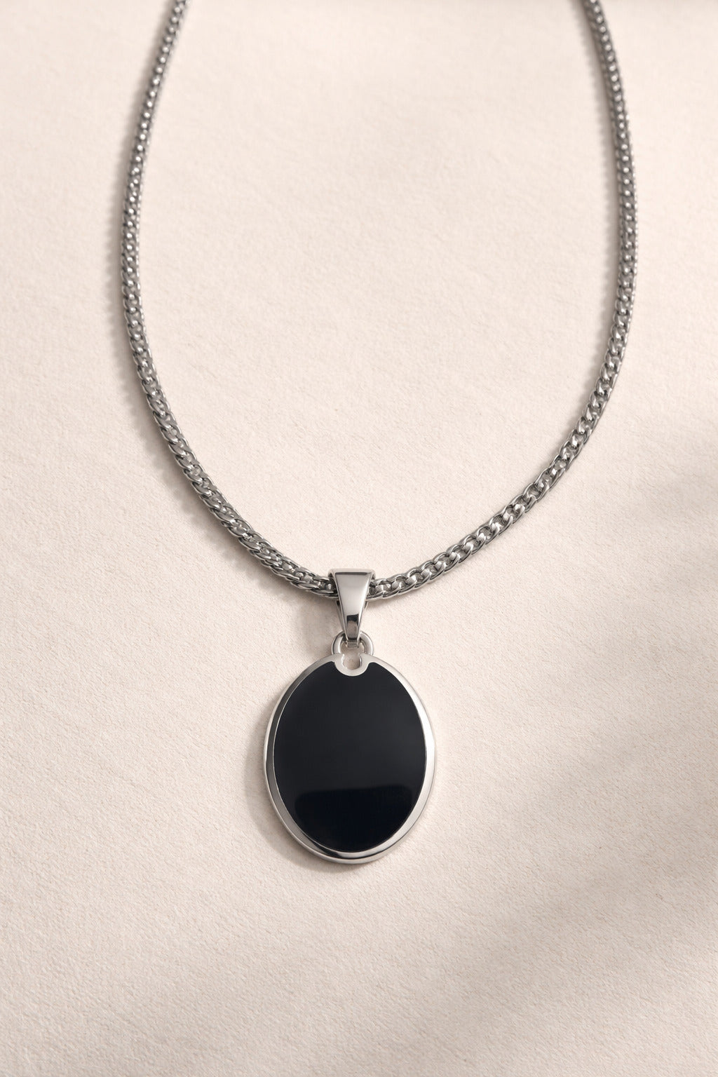 Necklace with a black pendant on a light beige background