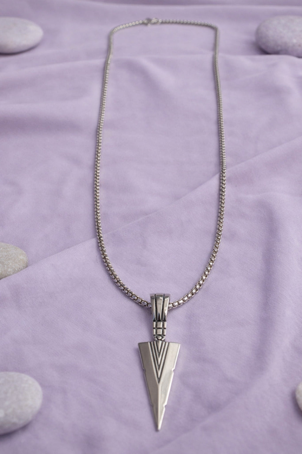 Silver necklace with a pendant on a purple fabric background