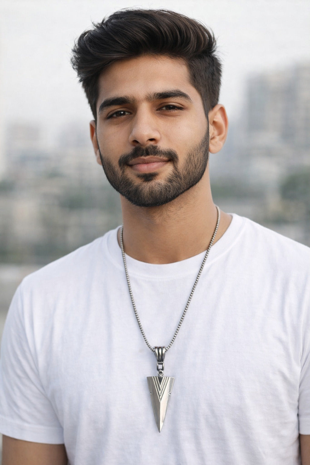 Man wearing a white t-shirt and a necklace with a cityscape in the background