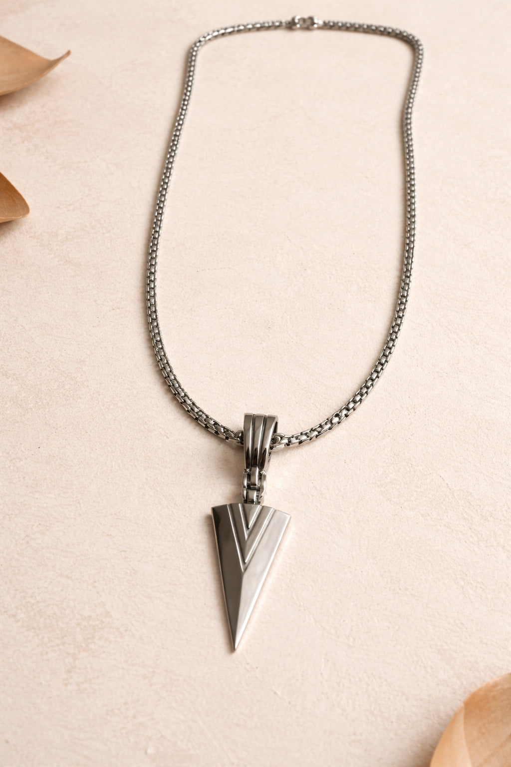 Silver necklace with a unique pendant on a beige background