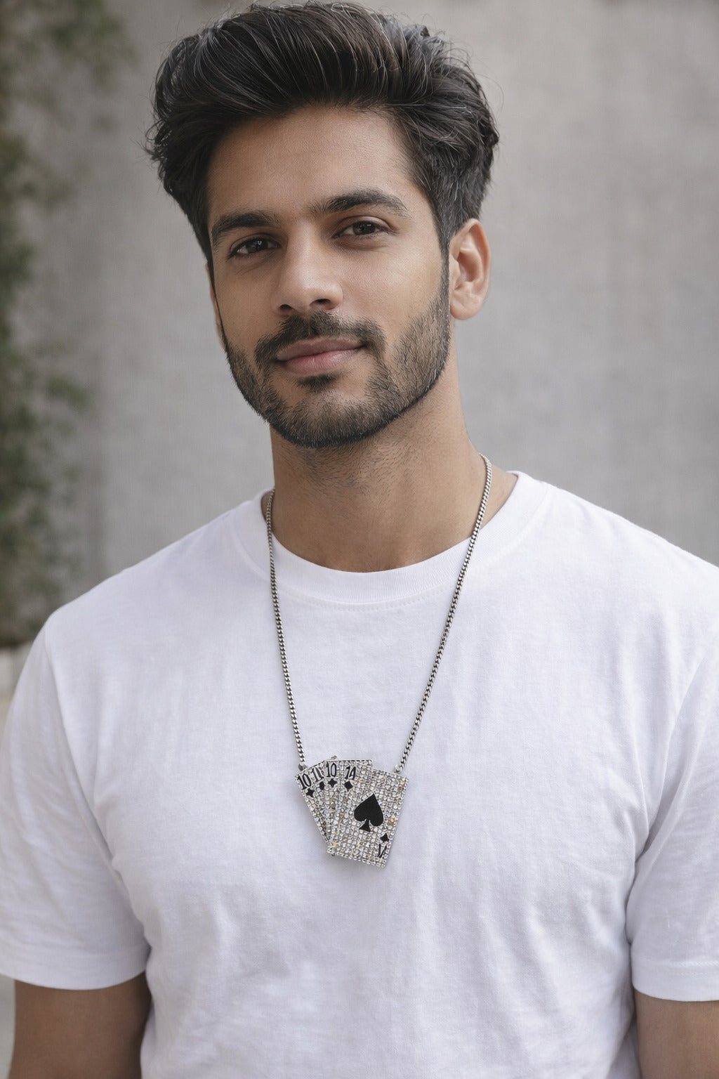 Man wearing a white t-shirt with a decorative necklace against a neutral background