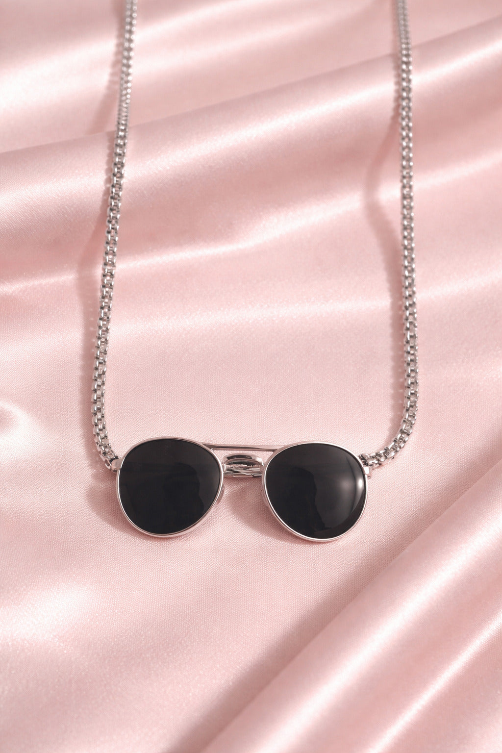 Necklace with black heart-shaped pendants on a pink satin background