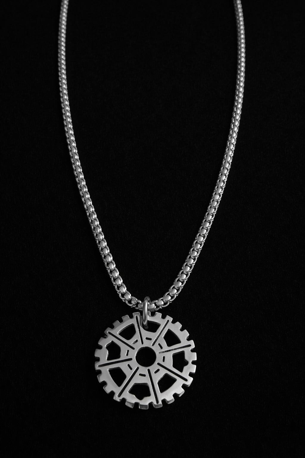 Silver necklace with a gear-shaped pendant on a black background