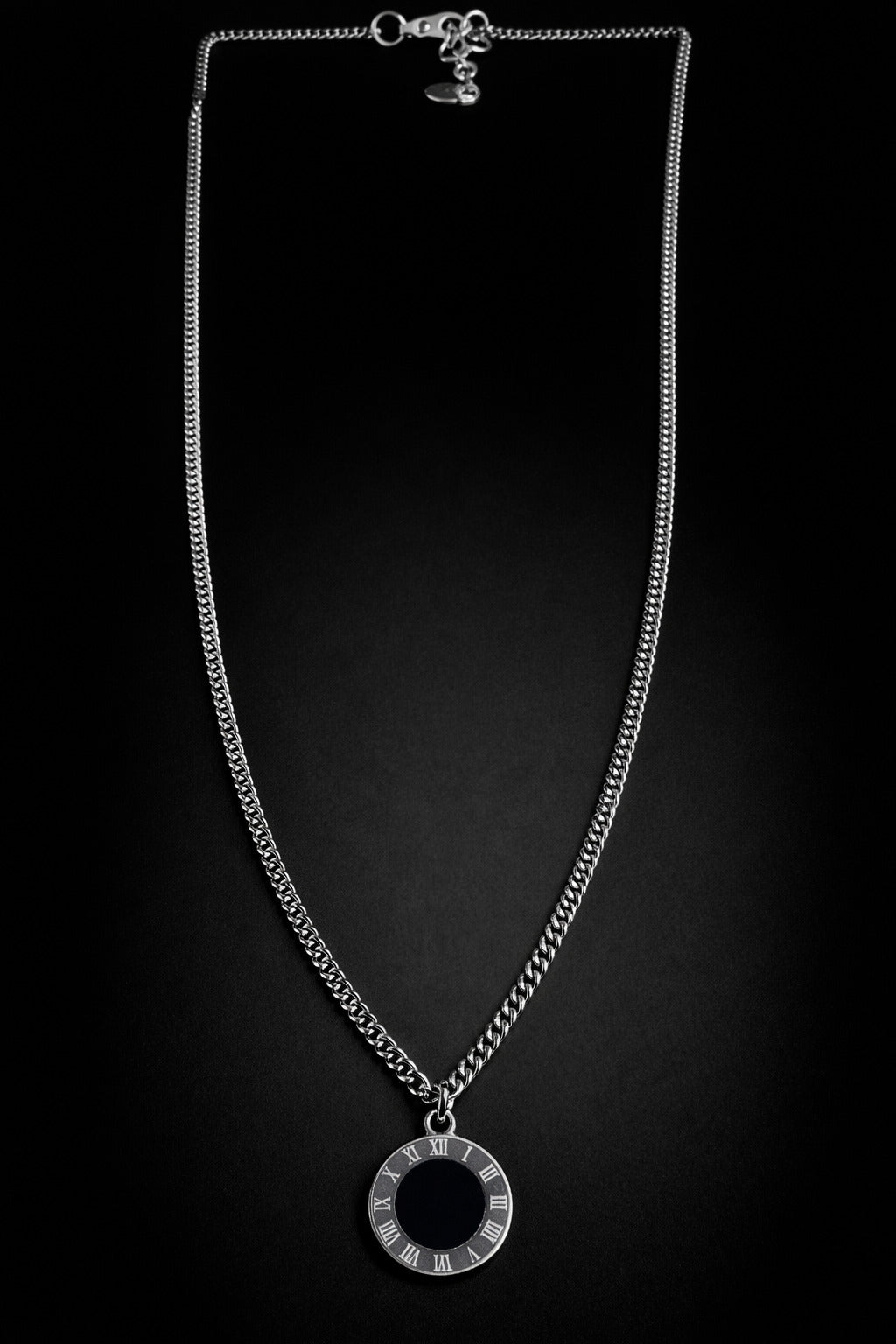 Silver necklace with a circular pendant on a black background