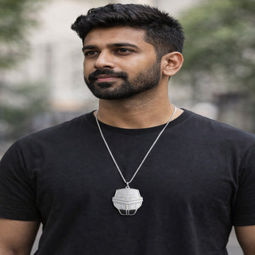 Man wearing a black t-shirt with a necklace featuring a pendant outdoors