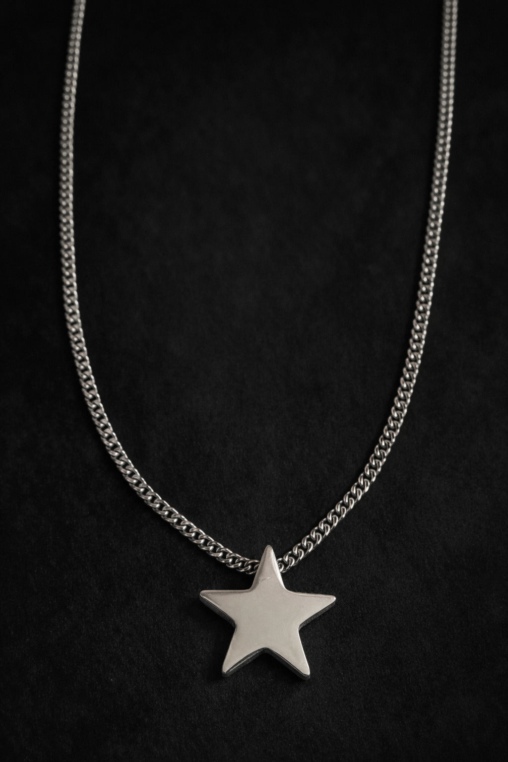 Silver star necklace on a black background