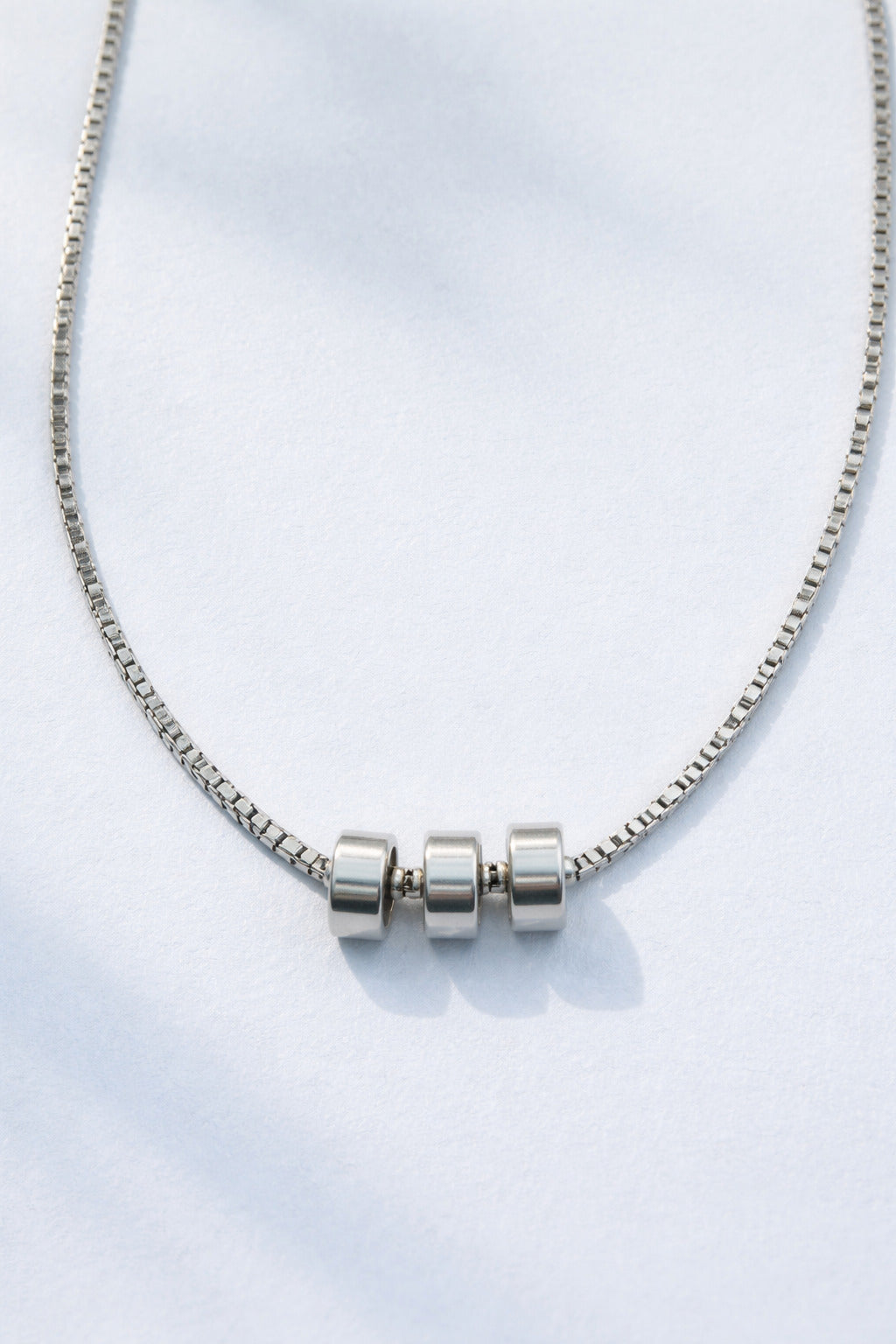 Silver necklace with cylindrical beads on a white background