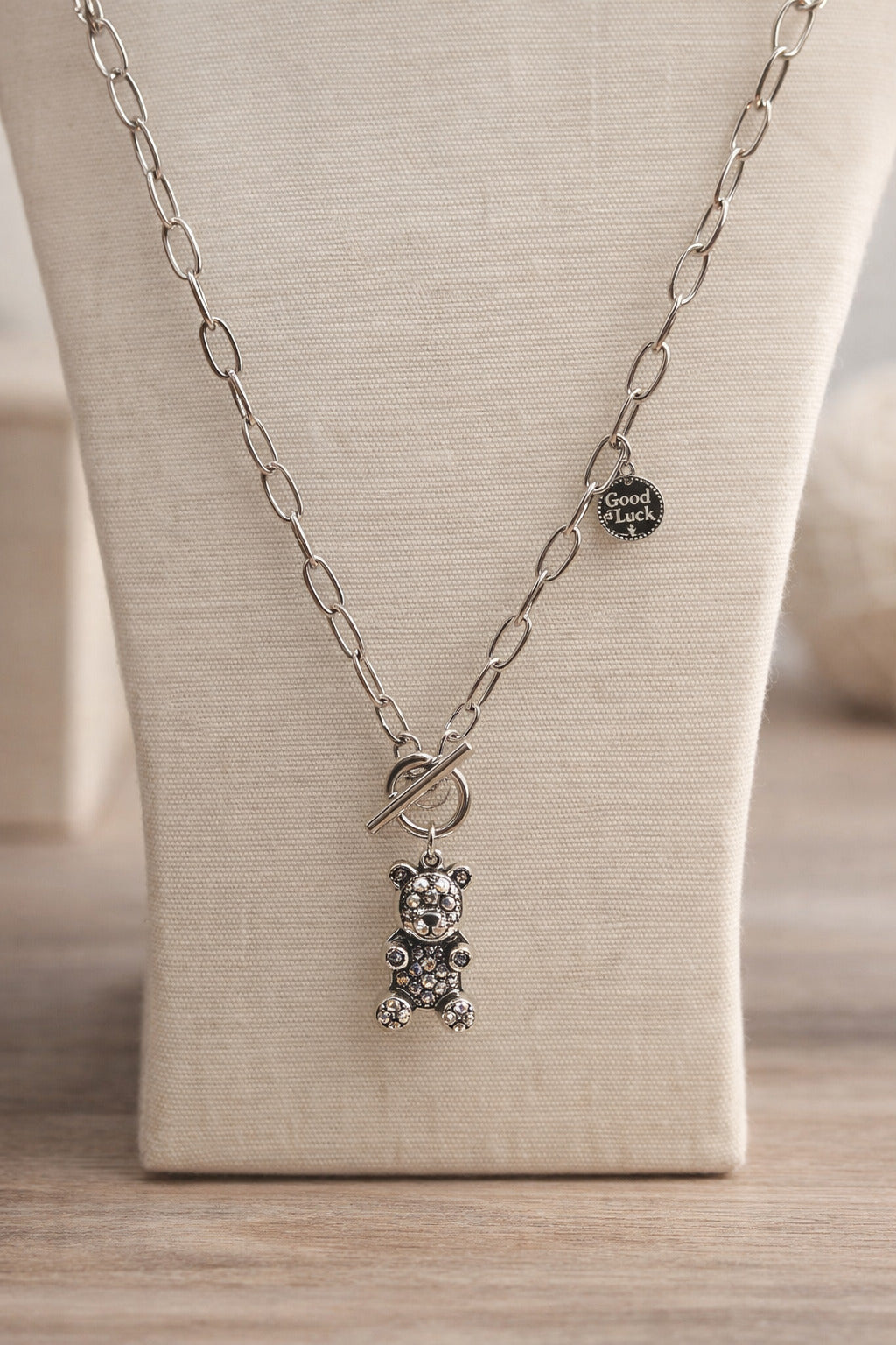 Silver necklace with a bear pendant on a mannequin bust.