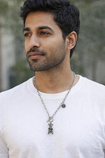Man wearing a white shirt and necklace with a blurred background