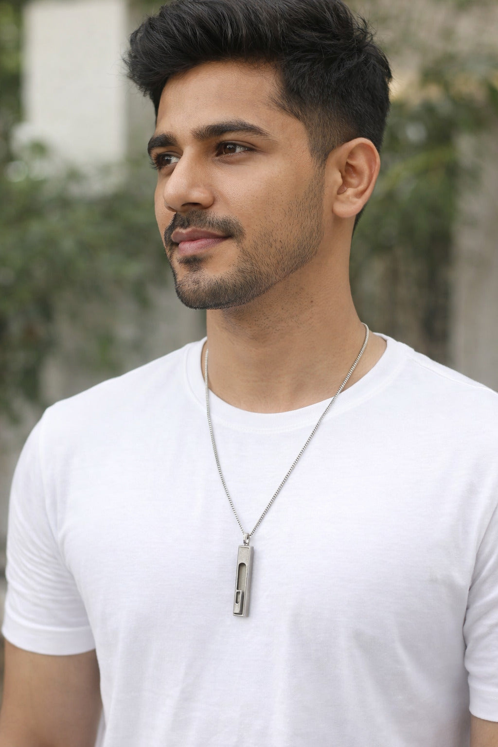 Man wearing a white t-shirt with a blurred outdoor background
