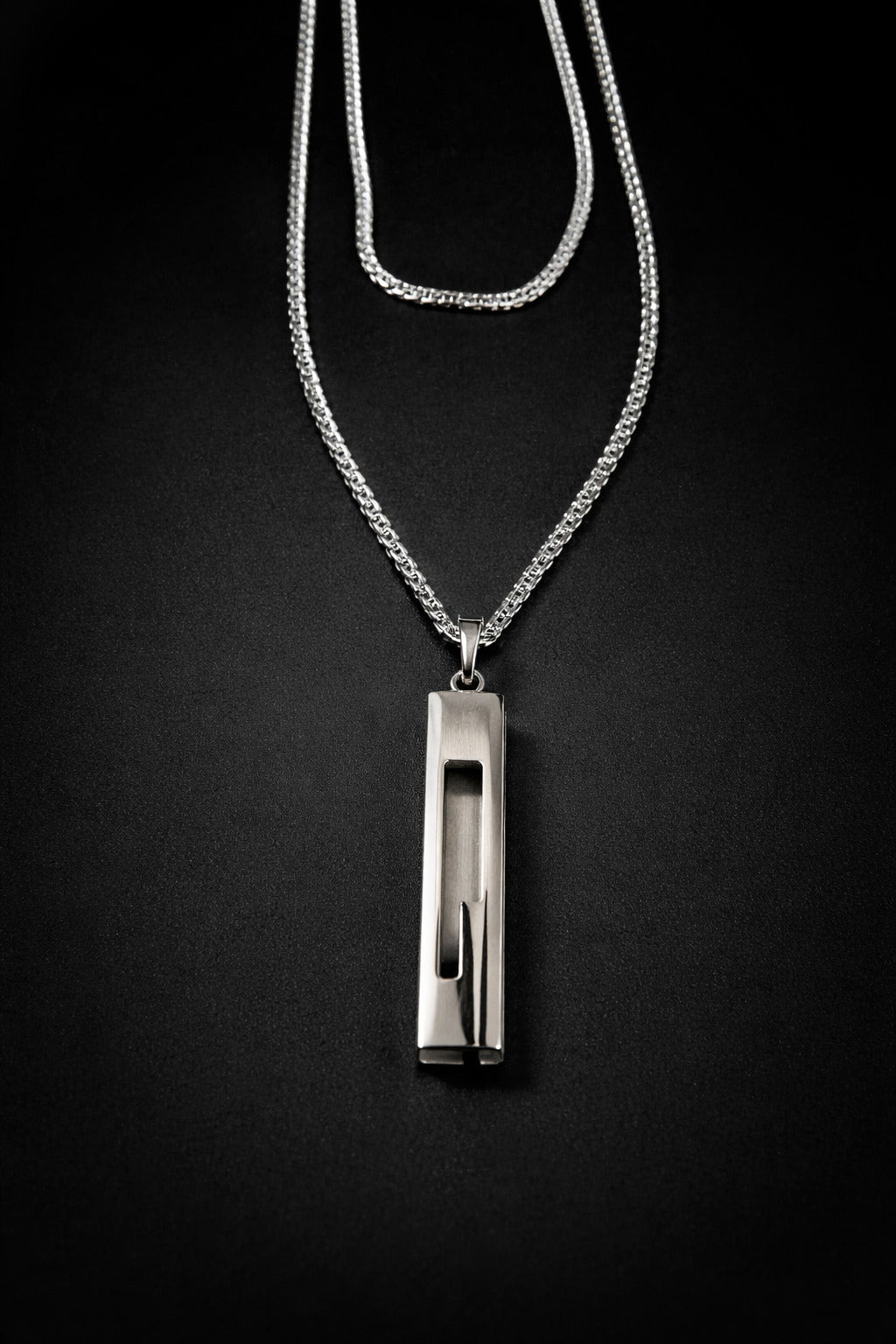 Silver necklace with a pendant on a black background