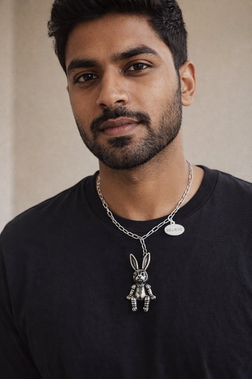 Man wearing a black shirt with a unique necklace featuring a rabbit pendant.