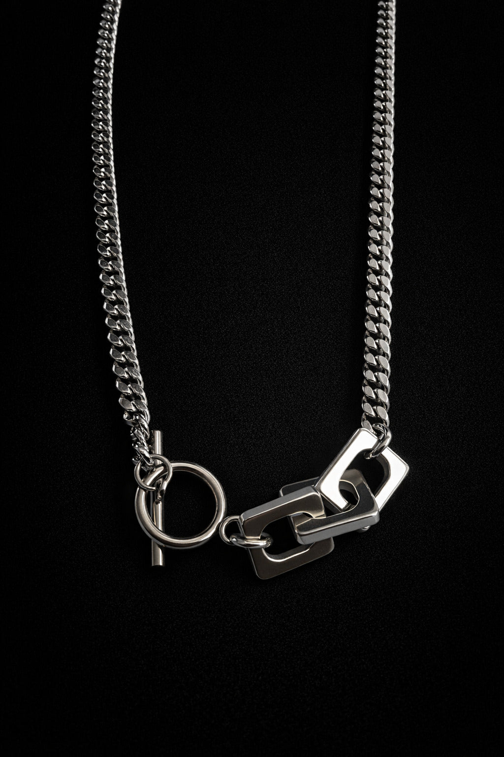 Silver chain necklace with a unique clasp design on a black background