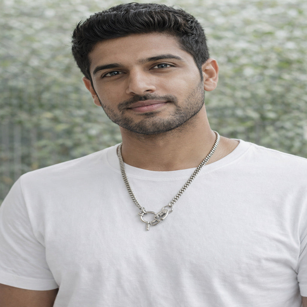 Man wearing a white t-shirt and necklace with a blurred natural background