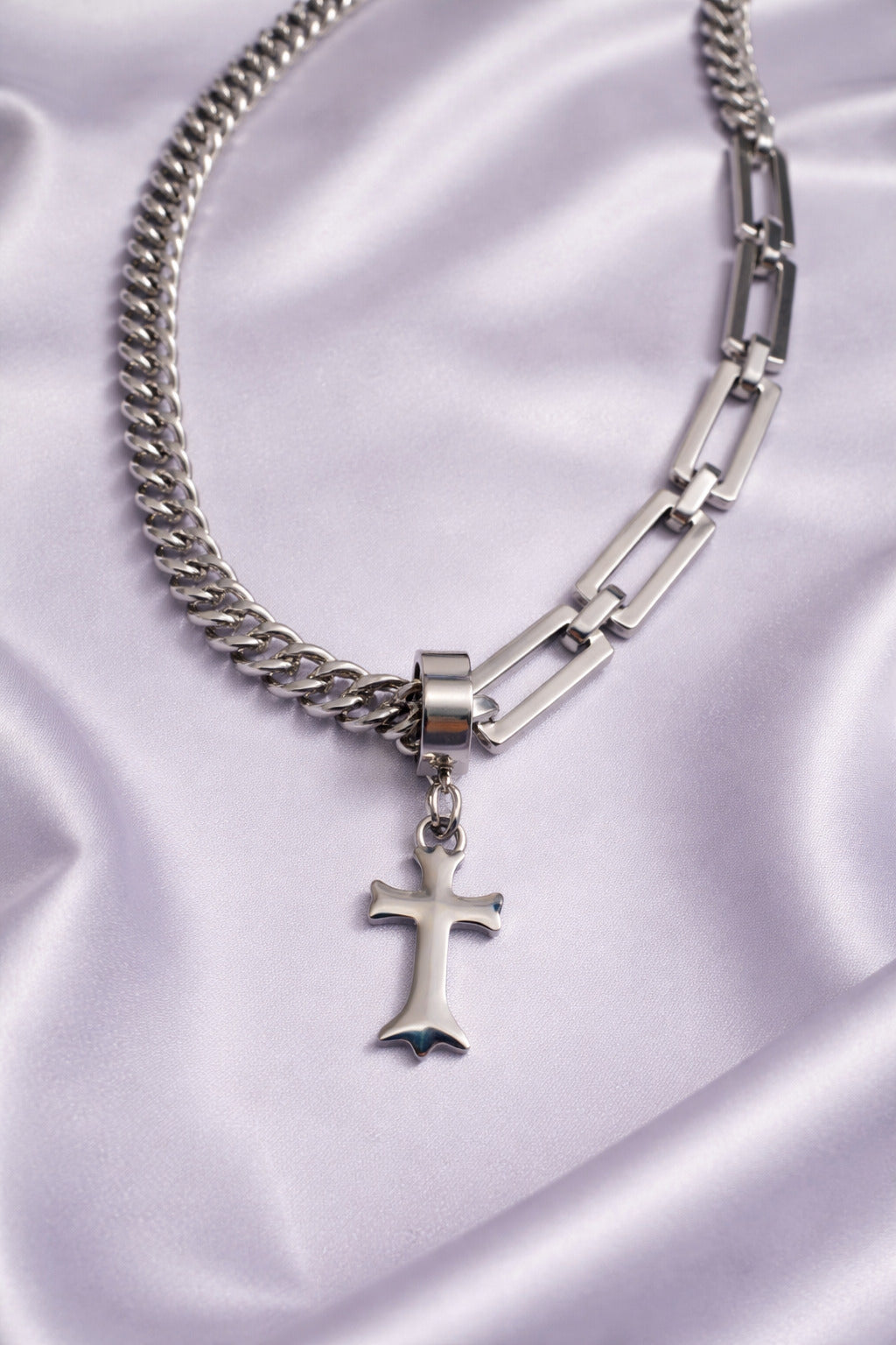 Silver chain necklace with a cross pendant on a satin background