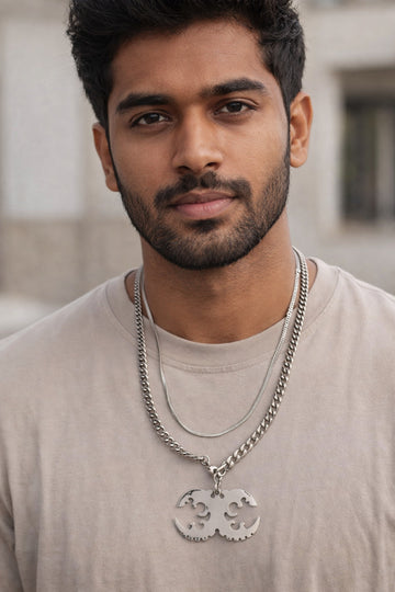 Man wearing a silver chain necklace with a pendant against a blurred background