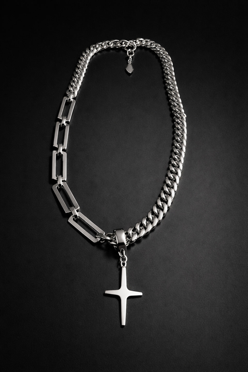 Silver chain necklace with a cross pendant on a black background