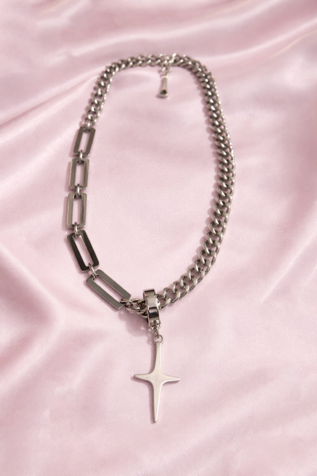 Silver chain necklace with a star pendant on a pink satin background