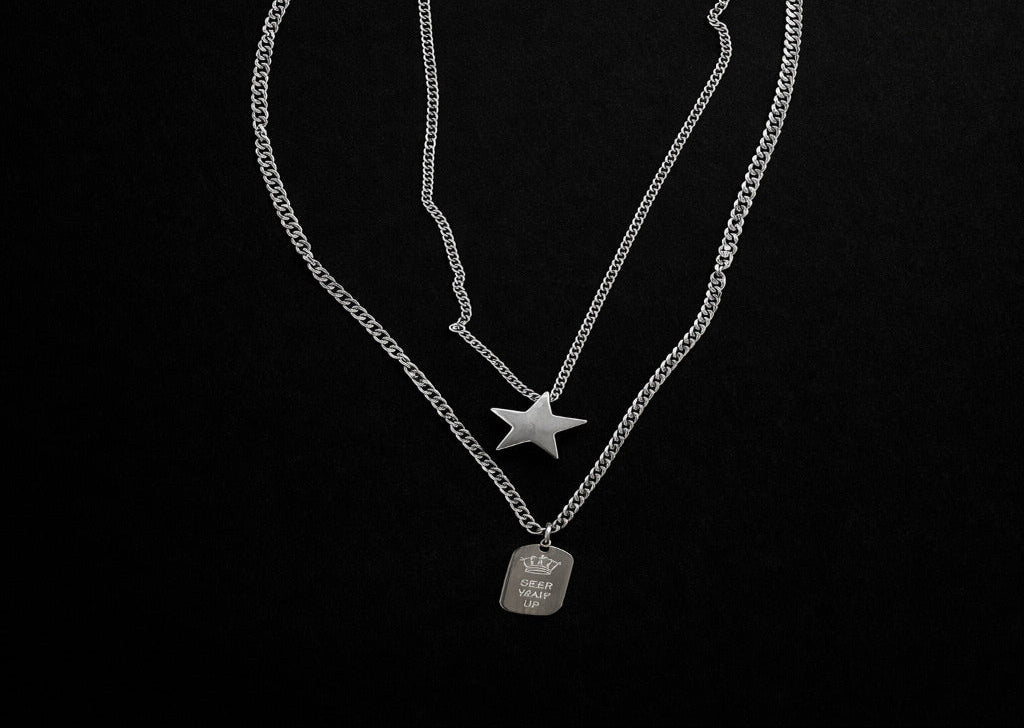 Two silver necklaces with star and crown pendant on a black background