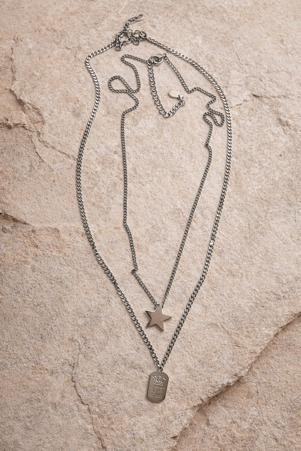 Necklace with star and dog tag pendants on a stone surface