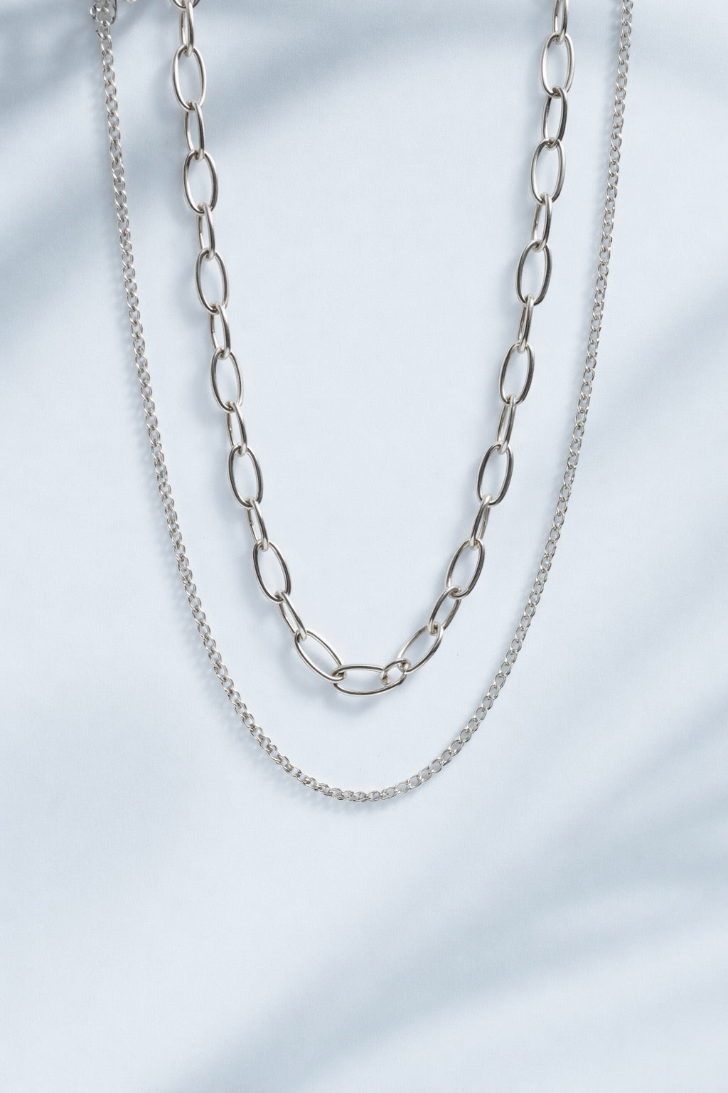 Silver chain necklace on a light gray background