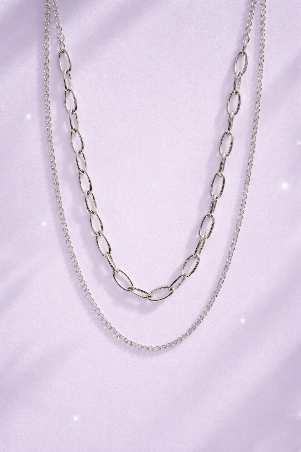 Silver chain necklace on a light purple background