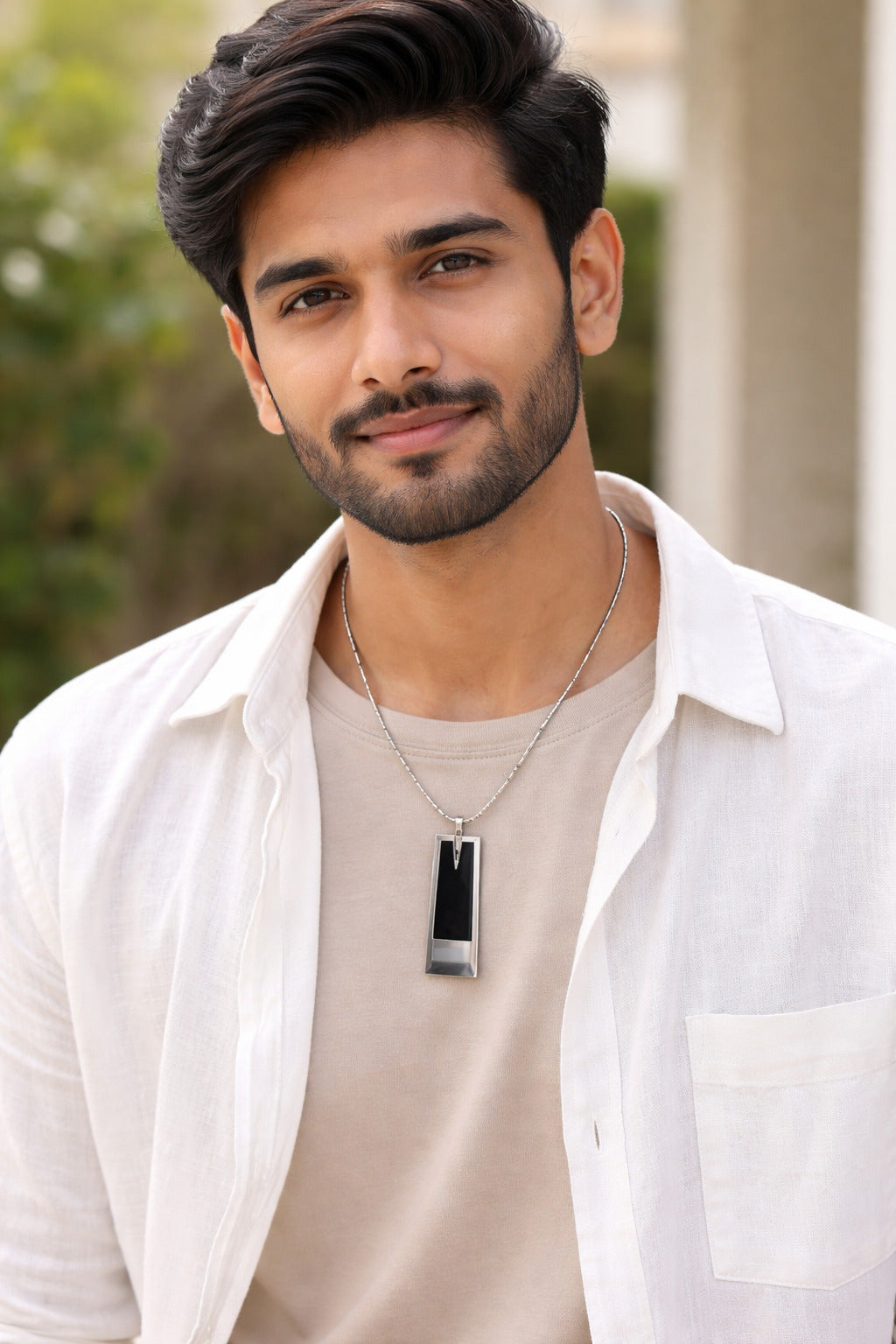 Man wearing a white shirt and necklace with a blurred background