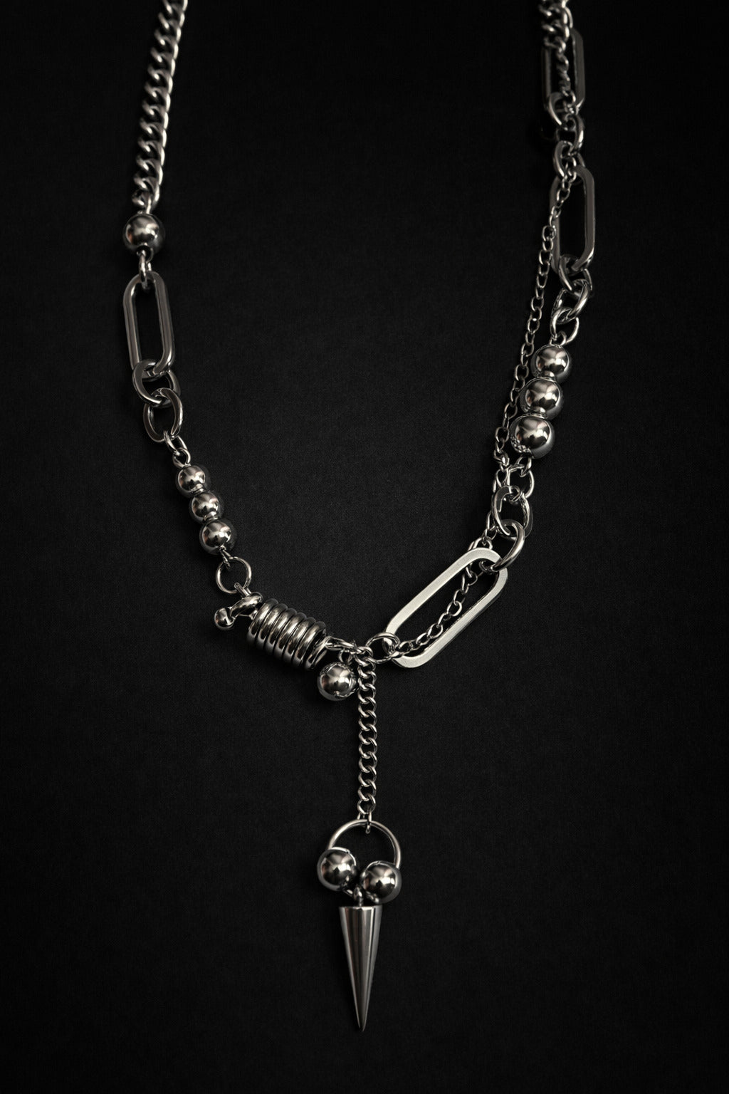 Silver chain necklace with a spike pendant on a black background
