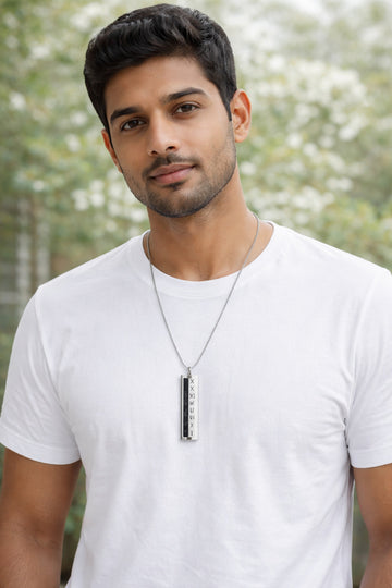 Man wearing a white t-shirt and necklace with a blurred natural background