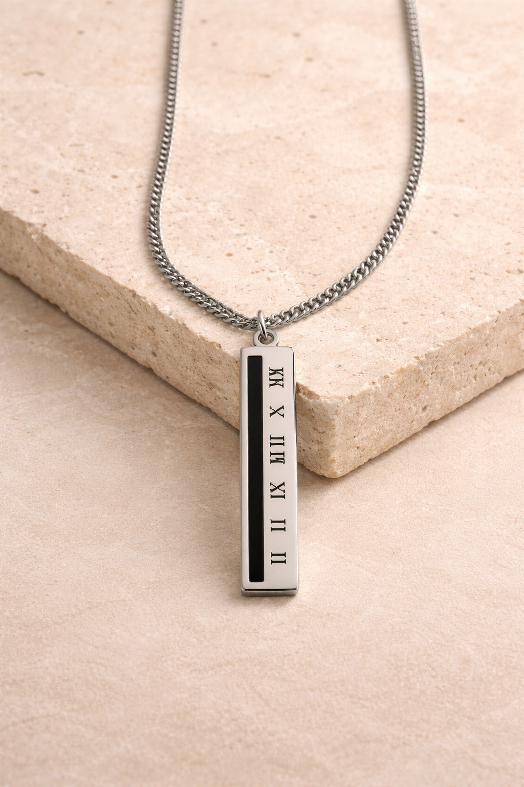 Silver necklace with a bar pendant on a beige surface