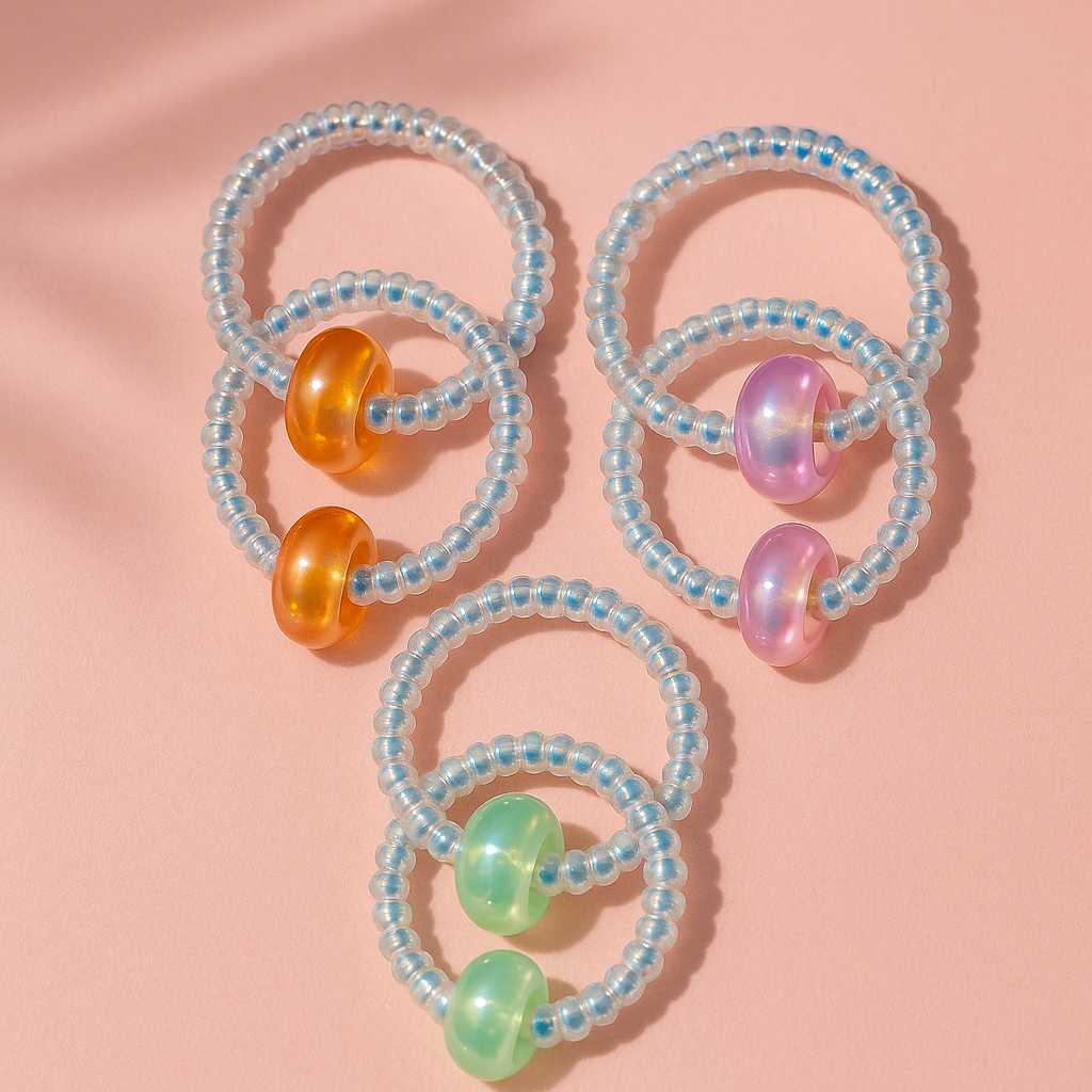 Three beaded hair ties with colorful beads on a pink background