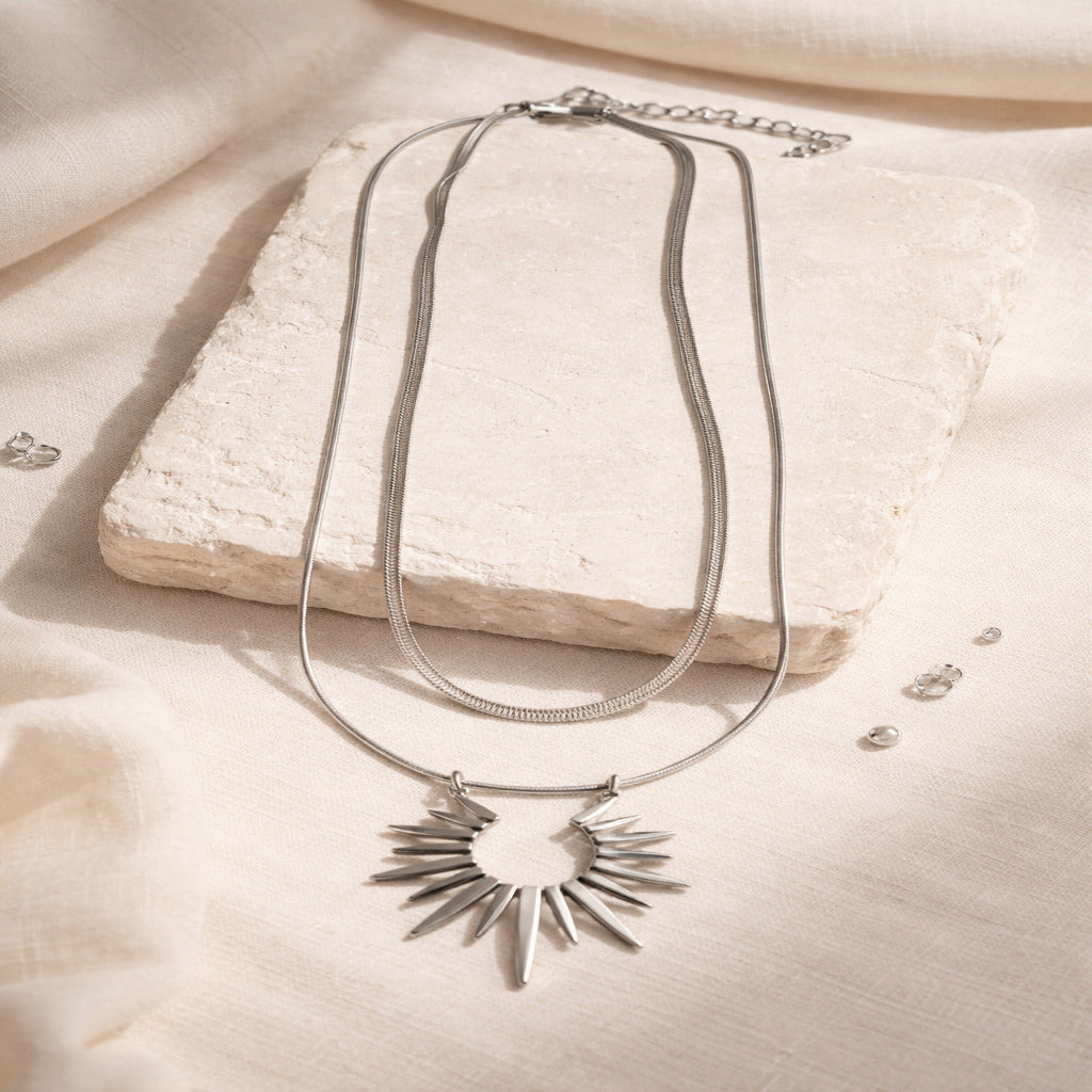 Silver necklace with a sunflower pendant on a beige surface