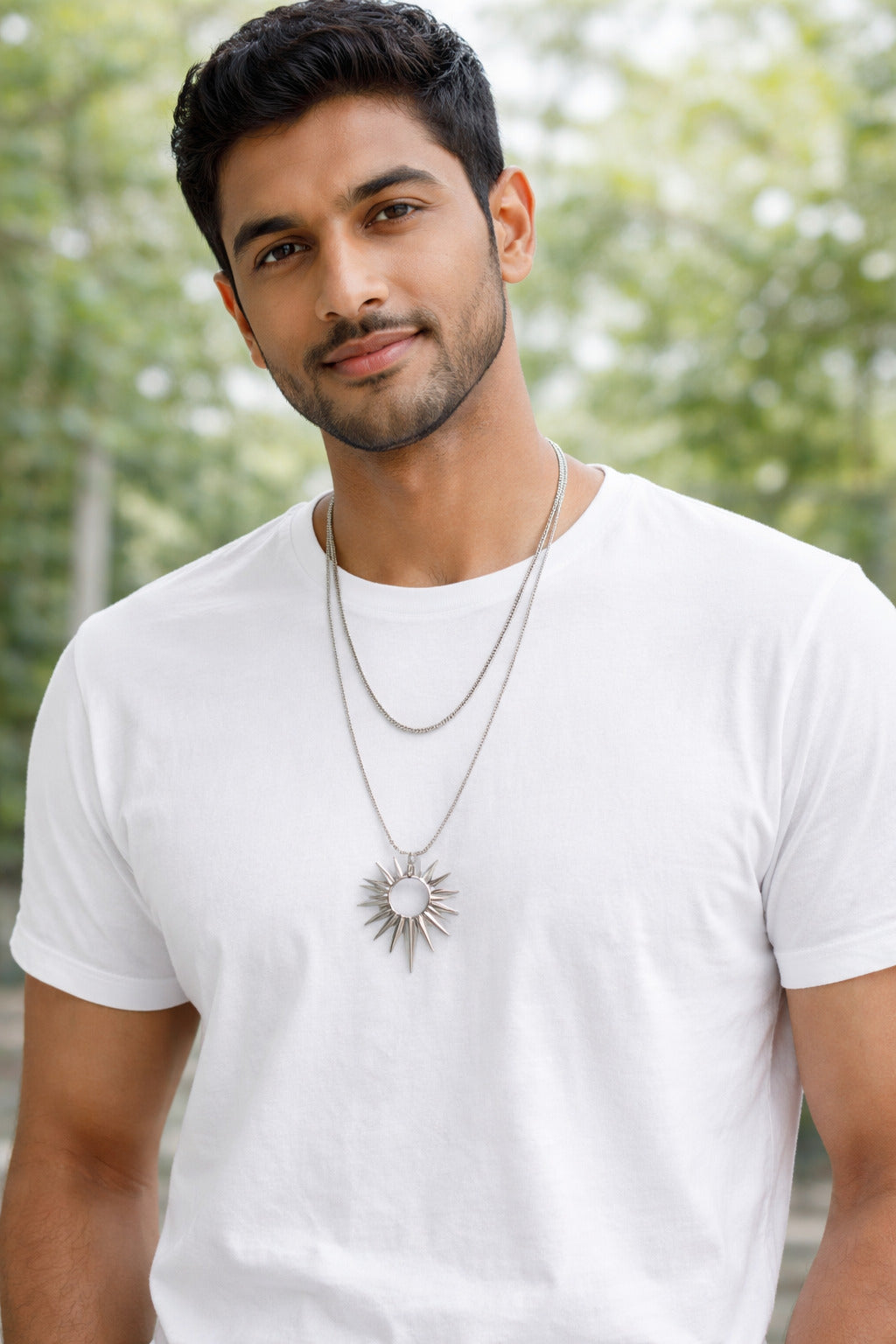 Man wearing a white t-shirt and necklace with a blurred green background
