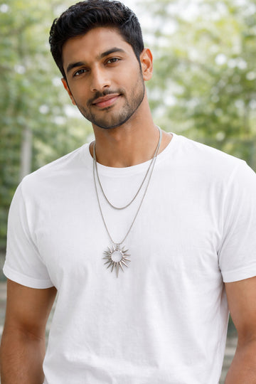 Man wearing a white t-shirt and necklace with a blurred green background
