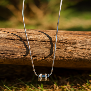 Necklace with a cylindrical pendant on a wooden log outdoors