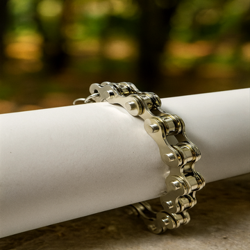 Gold chain bracelet on a white surface with a blurred green background