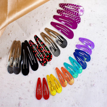 Assorted colorful hair clips on a textured surface with a brown fabric background.