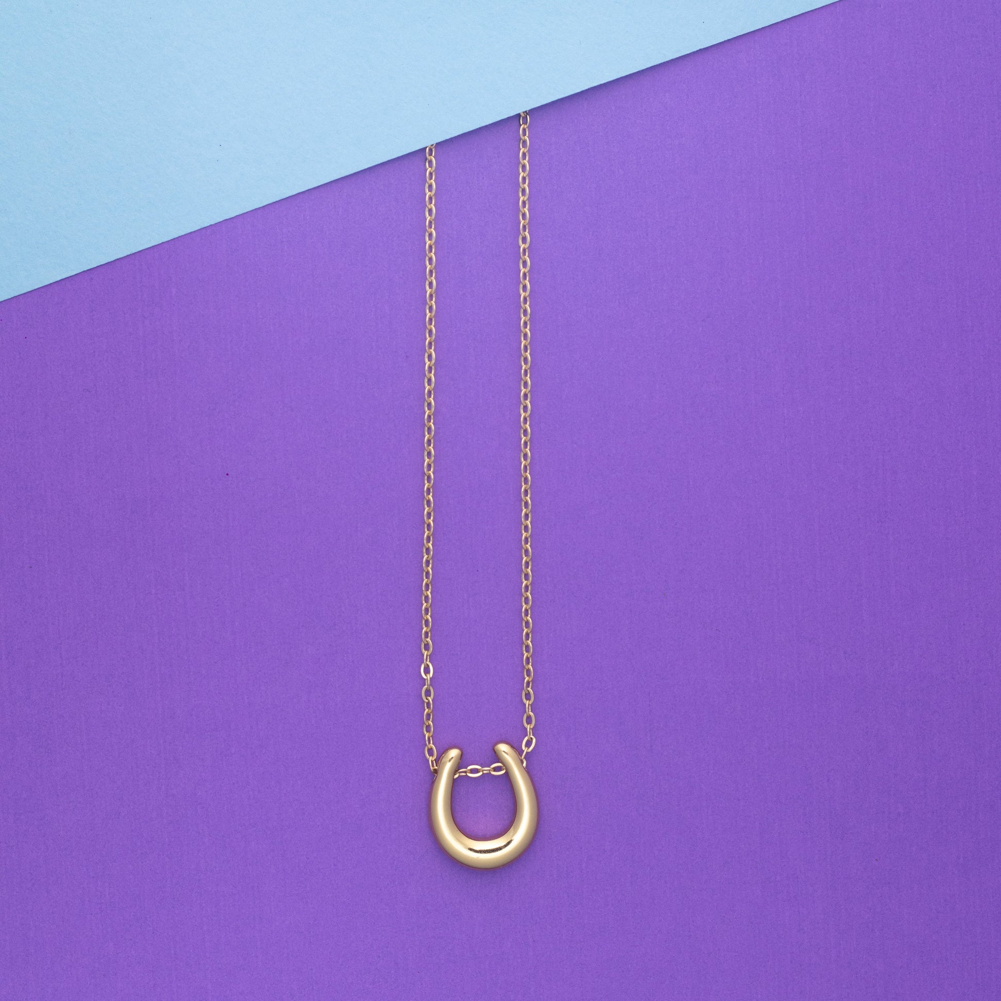 Gold necklace with a unique clasp on a purple and blue background